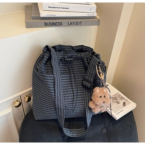 Detail view of plaid tote bag with drawstrings and a cute brown teddy bear keychain charm