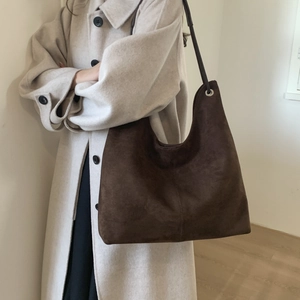 Detail of dark brown suede hobo tote bag with silver eyelets and wide shoulder strap