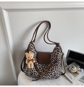 Detail of leopard print tote bag with brown leather trim and cute plush bear charm