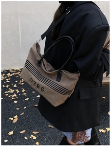 Close-up of brown striped canvas tote bag with adjustable shoulder strap and QZBG print