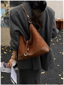 Brown suede hobo bag with contrast stitching and silver ring detail in autumn urban setting