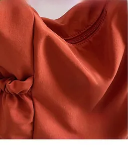 Detail view of terracotta fabric texture with side pleat design and zipper detail