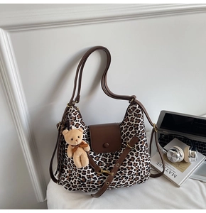 Detail of leopard print tote bag with brown faux leather trim and cute plush bear charm