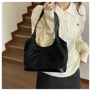 Detail of black suede bucket bag with ribbon drawstring and shiny leather base panel