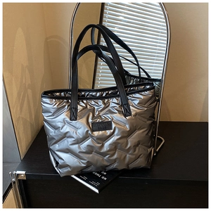 Detail of silver quilted tote bag showing metallic texture and black logo patch