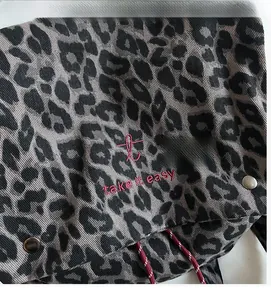 Close-up of leopard print canvas backpack with red embroidery and woven drawstring