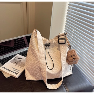 Detail view of a white quilted tote bag with drawstring closure and plush puppy charm