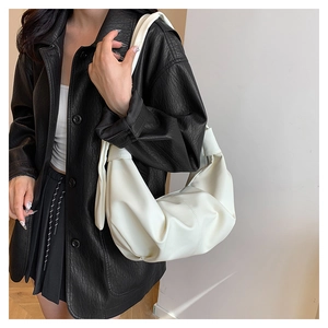 Close-up of a white pleated crescent shoulder bag featuring a wide strap and soft texture
