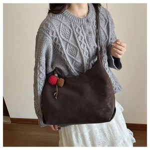 Détail du sac cabas en cuir mat marron foncé avec lettrage CHUDON et breloques pompons
