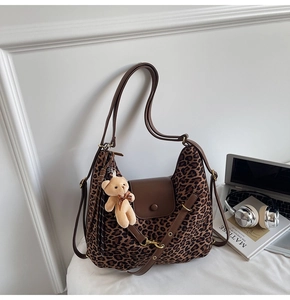 Detail of leopard print tote bag with brown leather flap and cute plush bear keychain