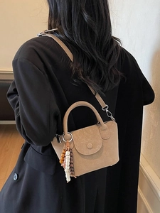 Elegant beige crossbody small square bag with decorative beads on a black blazer