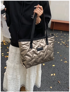 Detail of champagne gold quilted puffer tote bag with black leather shoulder straps