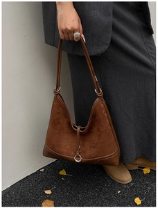 Detail of a dark brown suede hobo bag with silver buckle and shoulder strap in autumn style