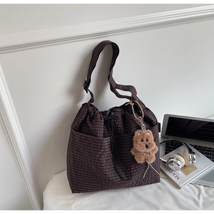 Detail of dark brown checkered bucket bag with drawstring closure and cute bear charm