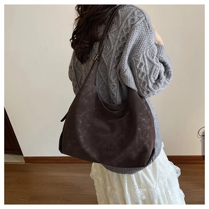 Détail d'un grand sac hobo marron avec le logo CHUDON embossé sur le cuir synthétique souple