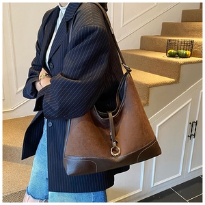Detail of dark brown suede tote bag with contrast stitching and adjustable metal buckle
