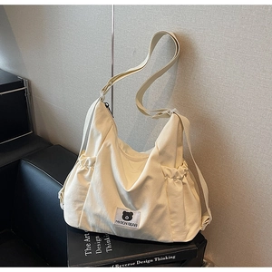 Dettaglio della borsa hobo in tela crema con patch a orsetto e tracolla regolabile