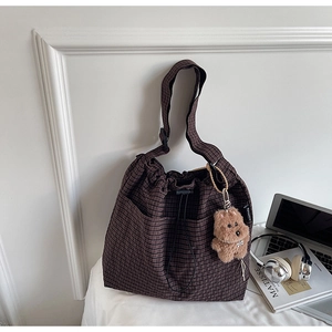 Detail view of brown checkered drawstring bucket bag with a cute plush bear charm