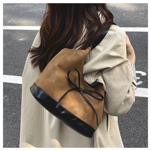 Detail of vintage bucket bag with contrast leather bow and suede texture outdoors