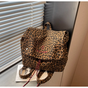 Detail of leopard print backpack with red embroidery and metal buckle on windowsills