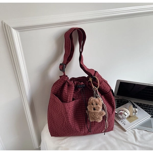 Detail of burgundy checkered drawstring bucket bag with cute brown bear charm