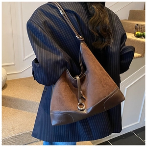 Detail of dark brown leather tote with suede panels and elegant metal ring buckle