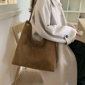 Detail of caramel suede tote bag featuring a metal eyelet and soft texture on shoulder
