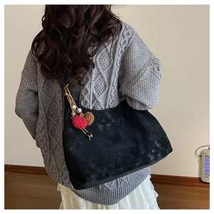 Détail d'un sac cabas vintage noir avec texture riche et pendentif en peluche coloré