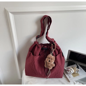 Detailed view of red plaid bucket bag with drawstring closure and cute bear charm