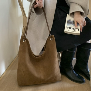 Detail of dark brown suede tote bag featuring silver metal eyelets and double straps