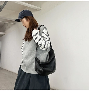 Détail du grand sac hobo en cuir noir montrant la texture et le drapé sur un mannequin