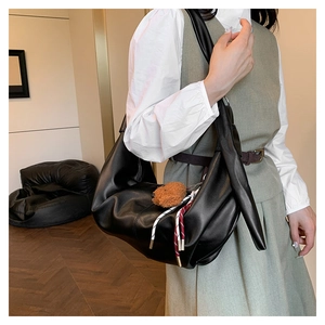 Detailed close-up of a black hobo bag featuring a cute plush bear pendant and cord detail