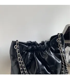 Détail du sac seau noir matelassé avec motif étoile et bandoulière en chaîne