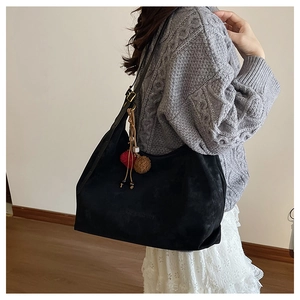 Détail macro du grand sac cabas noir en daim avec charme fraise et texture mate douce