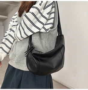 Détail du sac hobo noir en similicuir grainé avec fermeture éclair à pompon noué