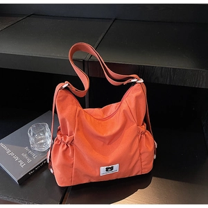 Dettaglio della borsa tote in nylon arancione con tasche laterali e tracolla larga