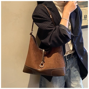 Close-up of a brown suede hobo bag with leather straps and metal ring buckle detail