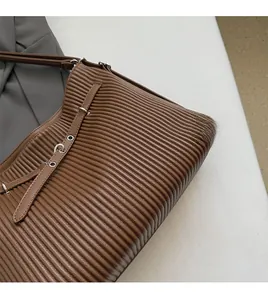 Detail of coffee brown pleated shoulder bag showing supple texture and metal eyelet adjustment