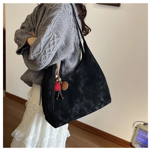 Détail du grand sac hobo noir avec texture à motif nuage et breloque pompon