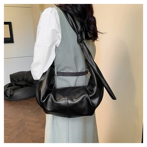 Detail of black crescent shoulder bag with knotted strap and pleated leather texture