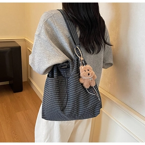 Detail of grey plaid drawstring bucket bag with a cute brown plush bear charm