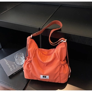 Dettaglio della borsa a tracolla plissettata arancione brillante con logo Myron Bear