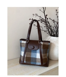 Detail of vintage plaid woolen tote bag with dark brown leather straps and metal buckle