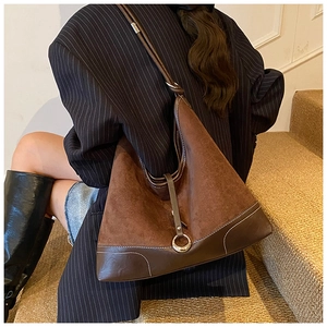 Detail of dark brown suede hobo tote bag featuring smooth leather trim and metal ring hardware
