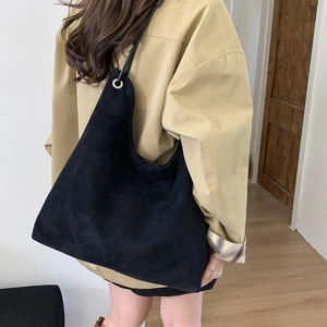 Model wearing a large black suede tote bag for daily commute and casual style