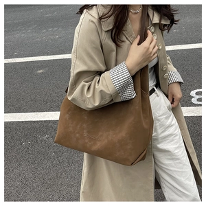 Photo de rue d'un grand sac cabas marron mat associé à un trench-coat beige élégant