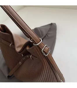 Close-up of brown pleated leather texture and polished silver metal buckle on the shoulder bag