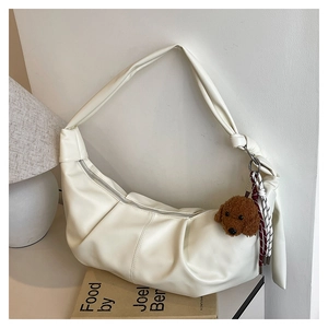 Detail of off-white pleated shoulder bag with cute brown teddy bear plush pendant