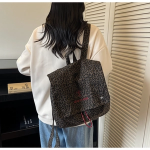 Detail of leopard print backpack featuring red 'take it easy' embroidery and drawstring