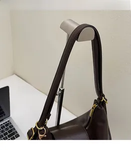 Detail of wide shoulder strap with gold metal buckle on a dark brown faux leather tote bag